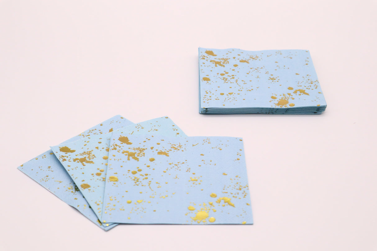 Set of blue napkins with gold splashes on a light pink background