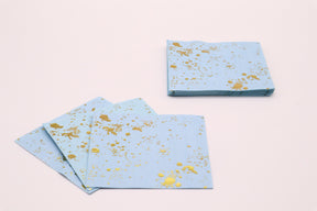Set of blue napkins with gold splashes on a light pink background