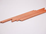 A set of metallic biodegradable paper straws in rose gold color, laid out on a white background.